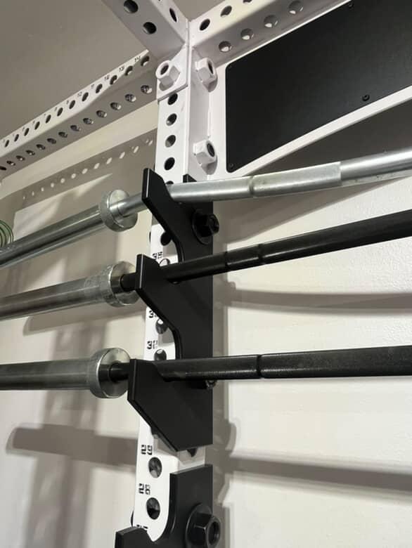 Gym rack with multiple bars attached to a white wall